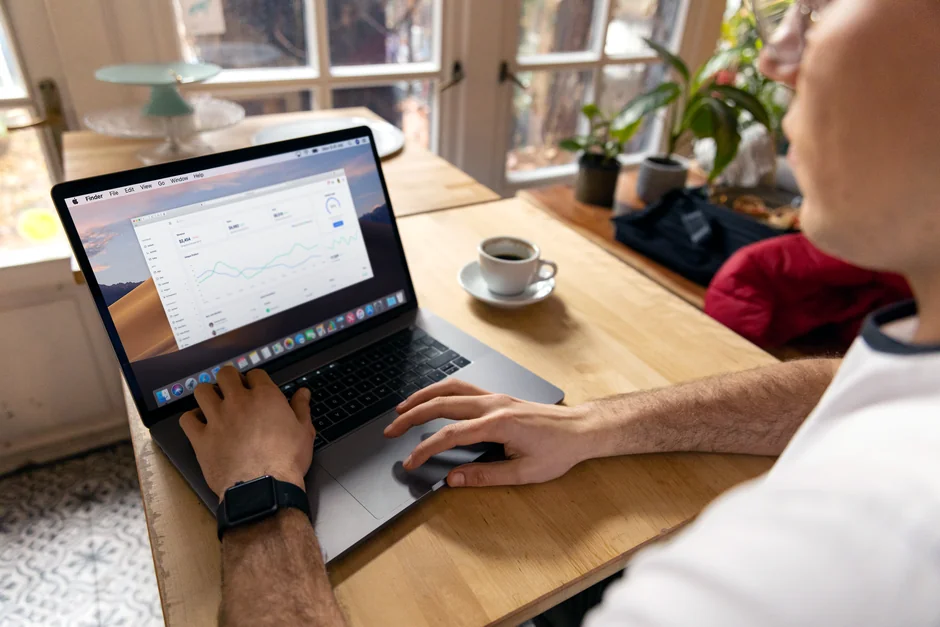 Two businessmen analyze stock market data using a smartphone and laptop in a modern office setting.
